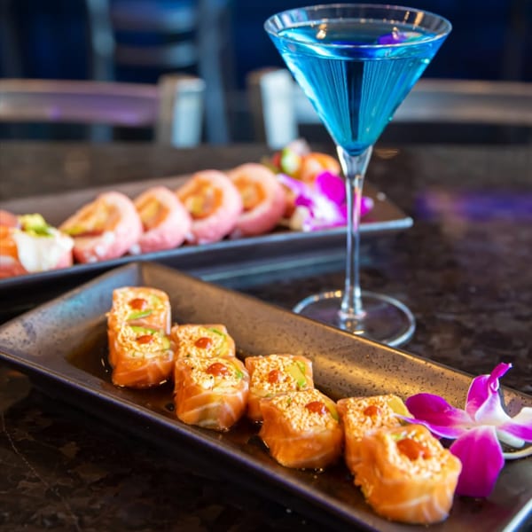 Blue Wasabi Sushi and Martini's sushi rolls and a blue martini on a dark table.